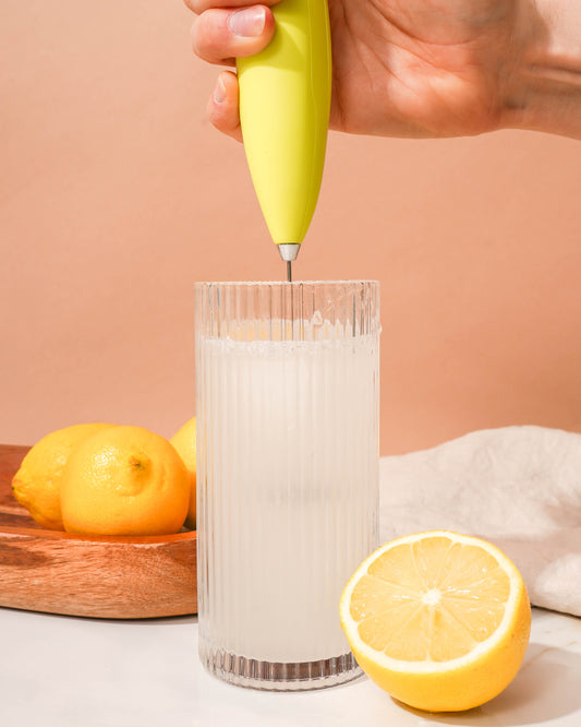 hand using an electric whisk to mix stevia free electrolytes in a cup
